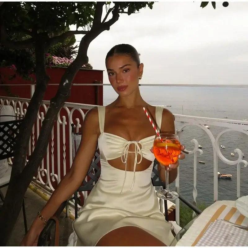 Model wearing mini dress with a cocktail on a balcony